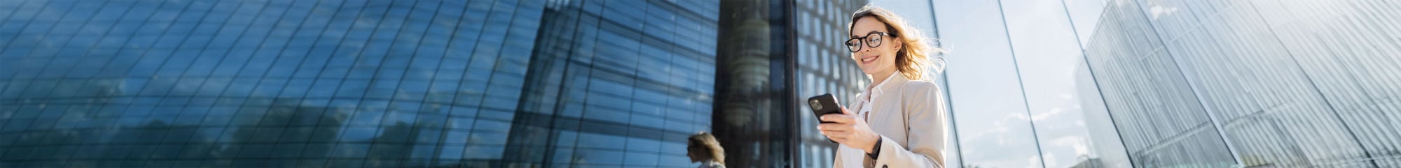 Smartphone and Tablet mockup showing a young business woman within skyscrapers scrolling her smarrphone