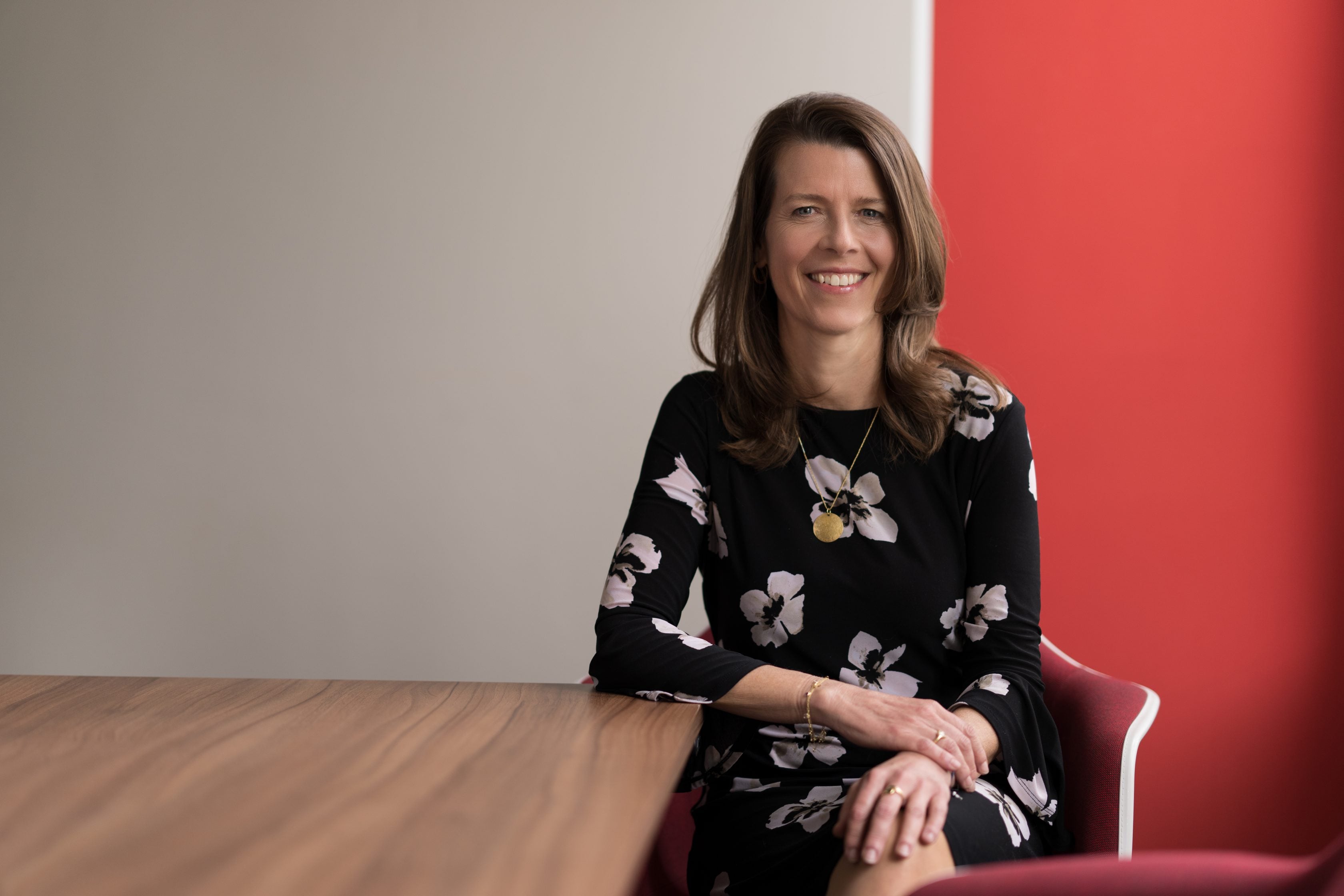 Photograph of Barbara Karuth-Zelle seated at a desk, adorned with a warm smile