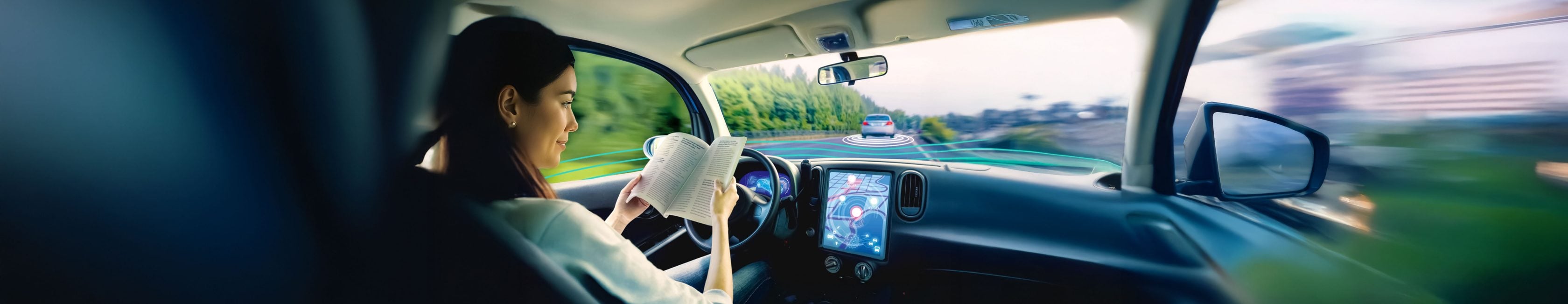 Frau liest ein Buch in einem selbstfahrenden Auto – Sinnbild für Komfort und Sicherheit automatisierter Fahrtechnik.