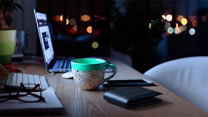 Laptop, Kaffeetasse, Smartphone und Geldbörse auf einem Schreibtisch bei Nacht – stehen für Finanzen, Arbeit und finanzielle Sorgen.