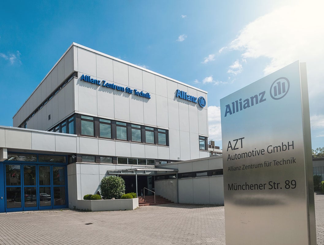 Außenansicht des Allianz Zentrums für Technik in Ismaning bei München mit Firmenlogo unter blauem Himmel.