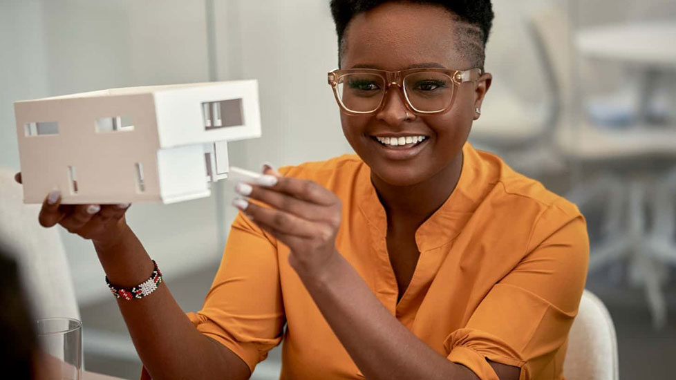 Frau zeigt ein klimafreundliches Hausmodell