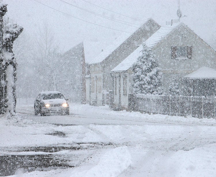 Stark beschneite Straße in Ortschaft 