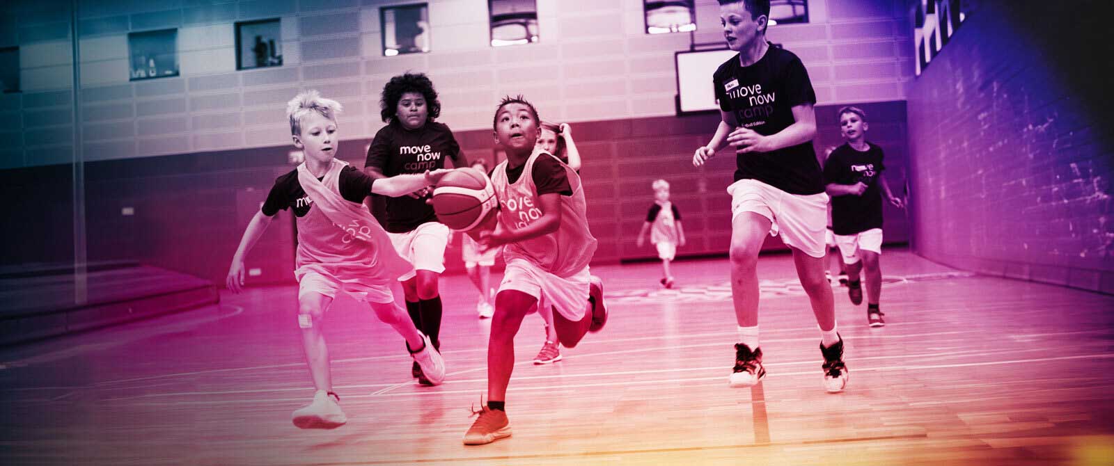 Kinder spielen Basketball, t-shirts mit movenow logo tragend