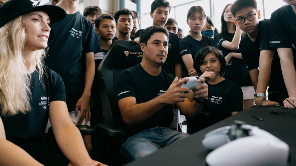 Eine Gruppe junger Leute steht zusammen und lacht, während sie ein Videospiel spielen.
