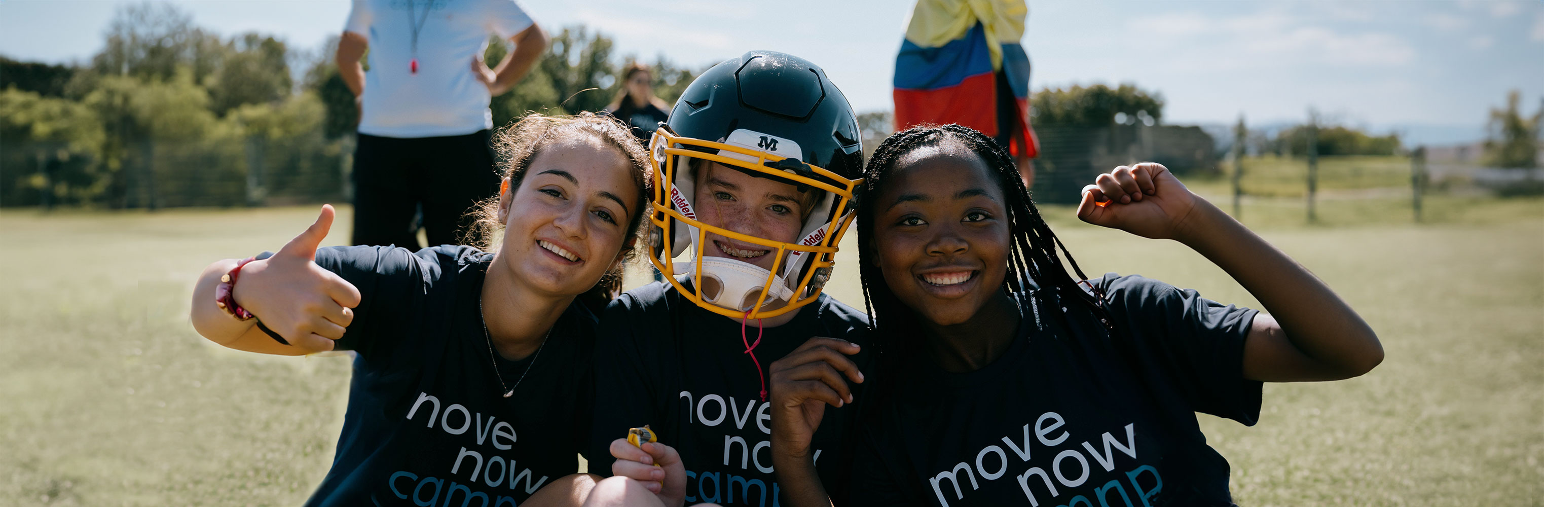 Drei junge Teilnehmerinnen des weltweiten MoveNow Camps blicken fröhlich in die Kamera