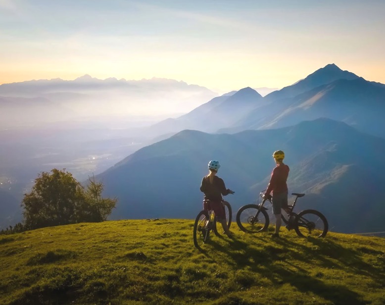 Two bikers on a mountain overlooking the idyllic alpine panorama