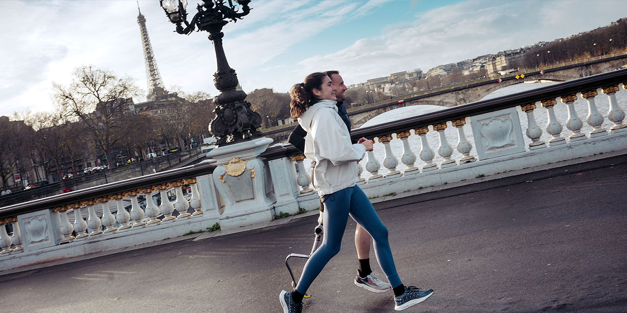 Triathletes Emma Lombardi and Jules Ribstein jogging across a bridge along the Seine in Paris
