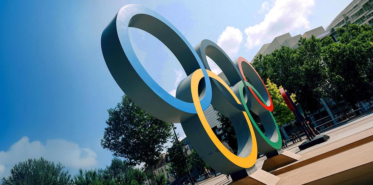 Olympic rings sculpture outdoors in a city setting, symbolizing the Olympic and Paralympic Movements and their global partnership with Allianz as an insurance partner.