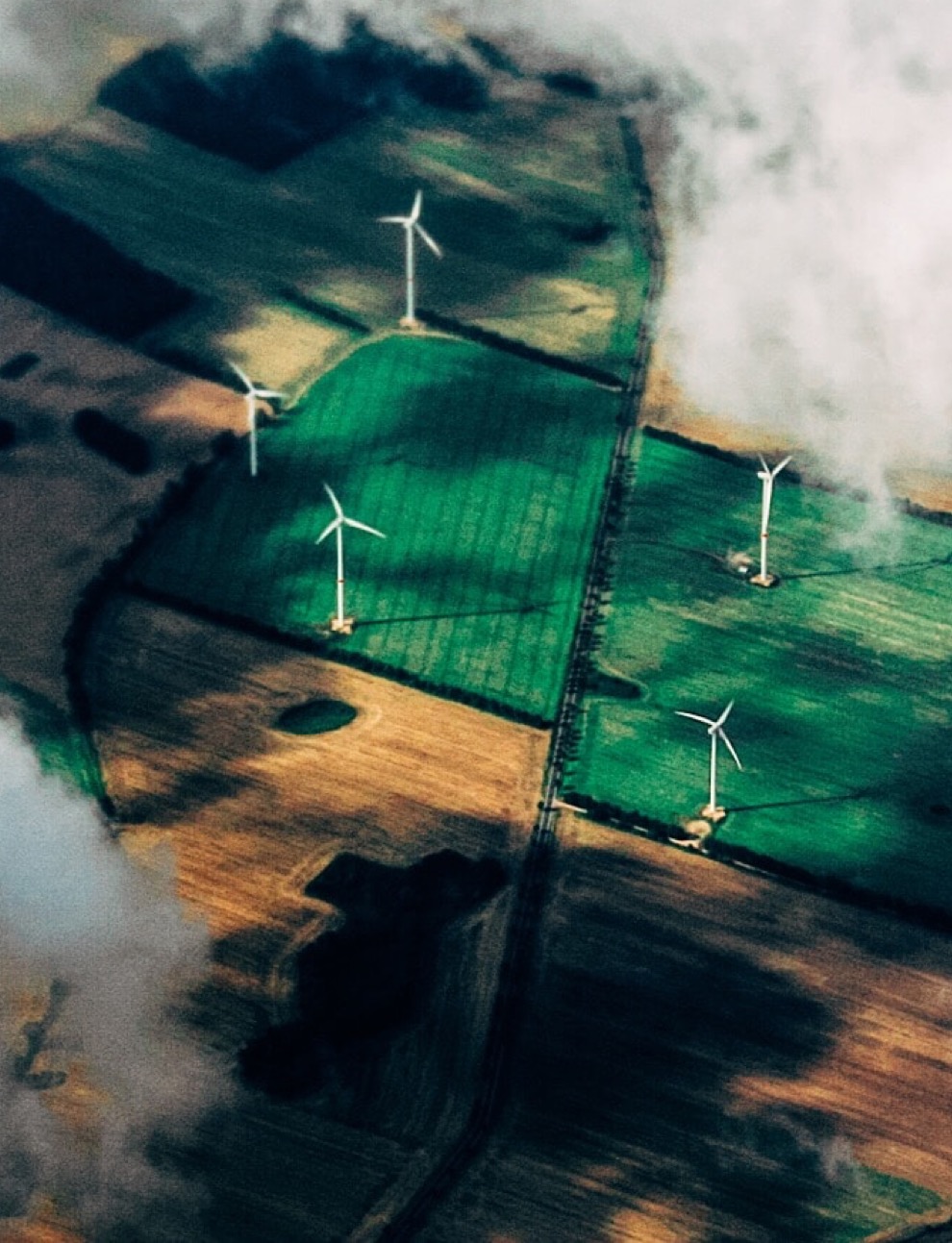 Wind turbines in a field between clouds from above