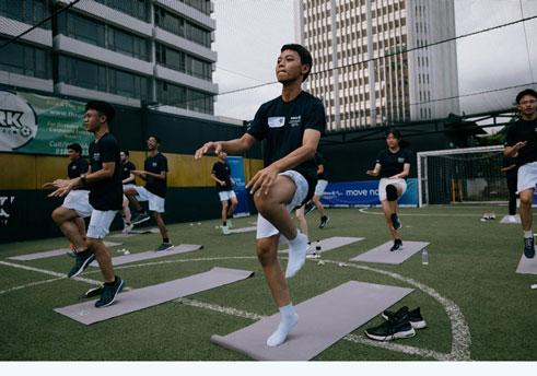 Young people excercising on outdoors on some yoga mats.