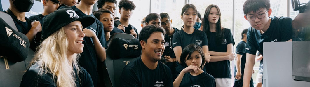 A group of young people standing together and laughing while playing a videogame.