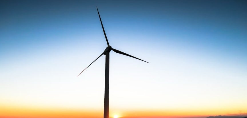 A windmill turns in front of a sunset