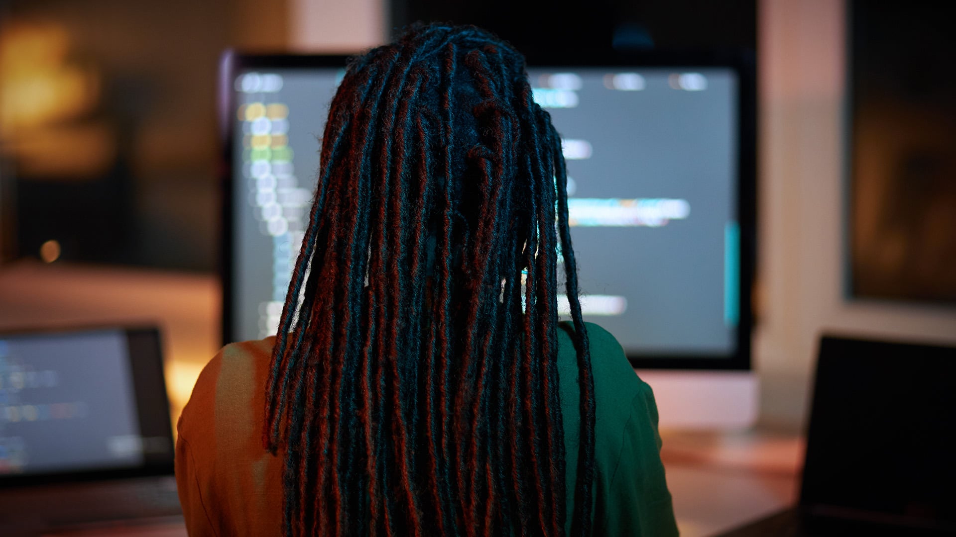 Woman with long dreadlocks working at a computer screen in an office.
