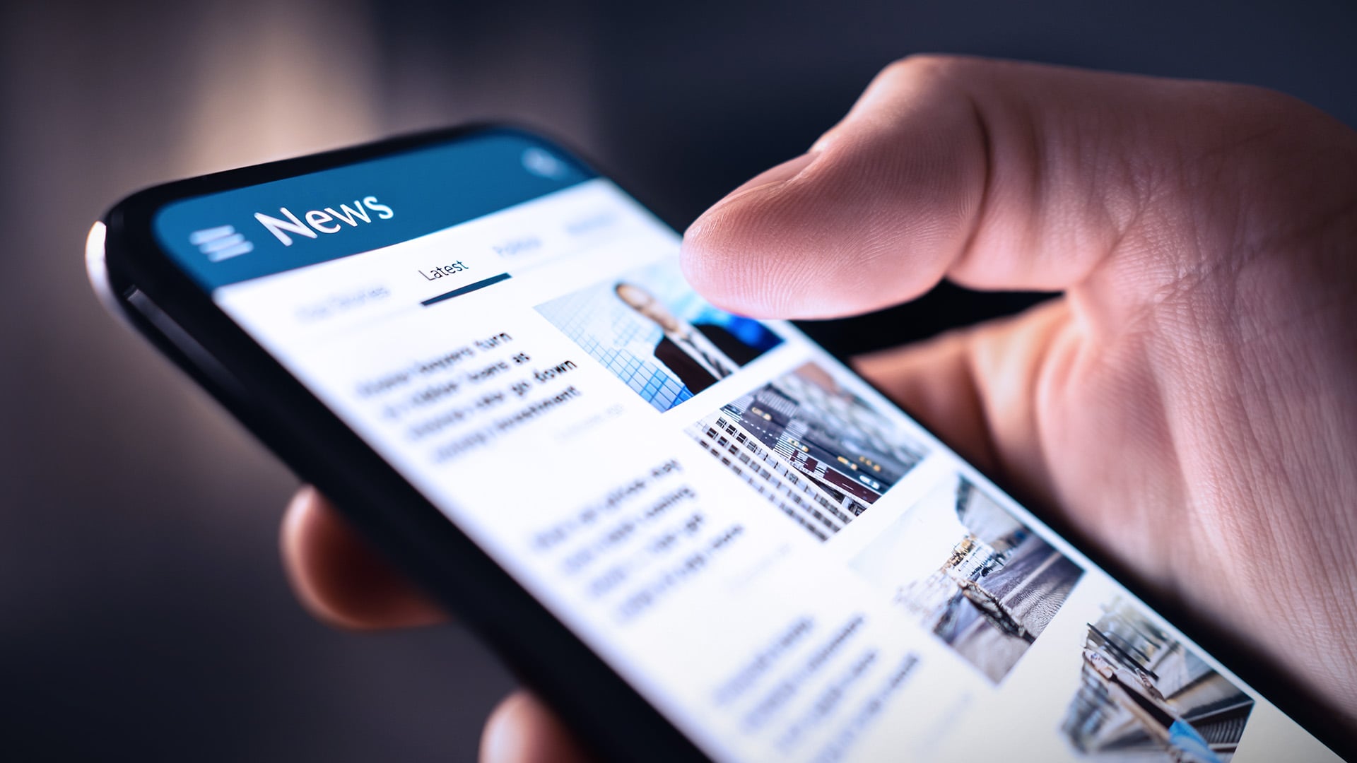 Hand holding a smartphone showing online news headlines.