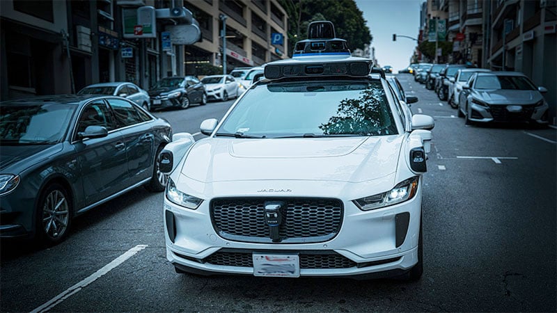 Autonomous robotaxi equipped with sensors and cameras driving in an urban environment.