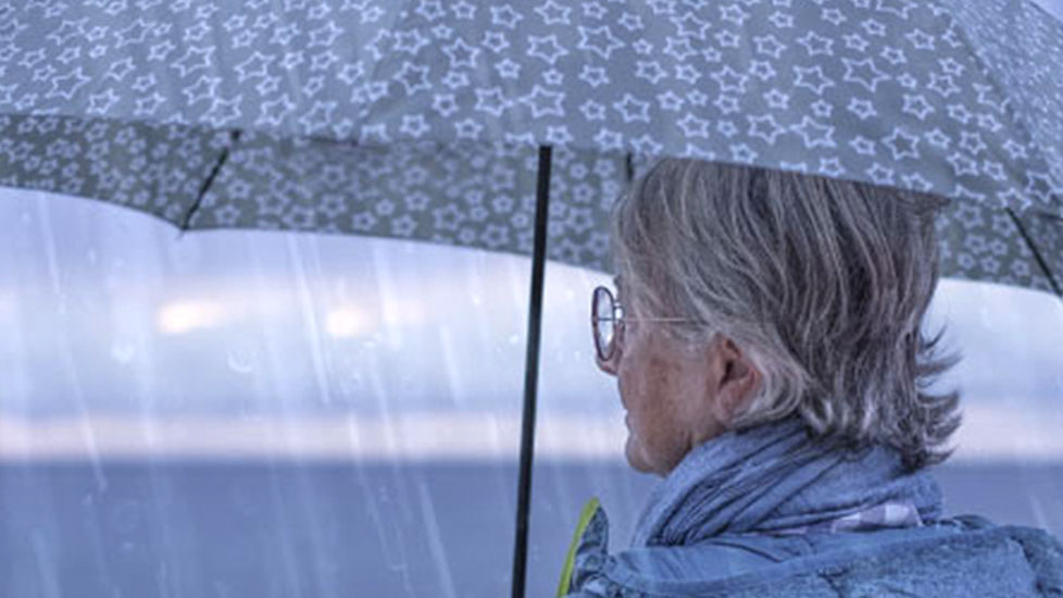 Elderly lady under an umbrella looks confidently toward the horizon