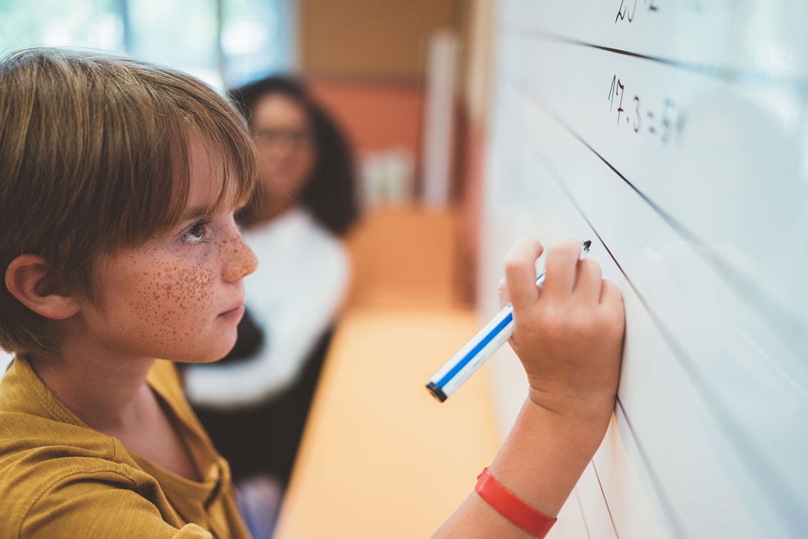Child writing on the blackboard at school