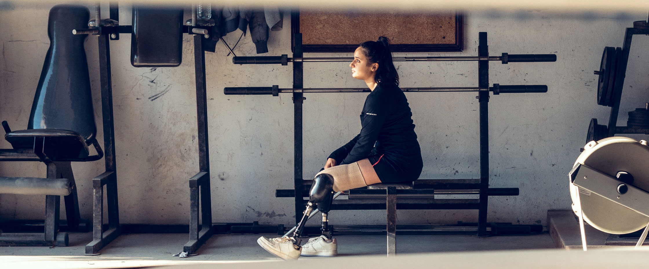 Athlete with prosthesis on leg sits in fitness room